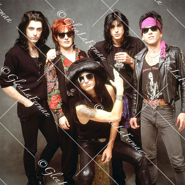 L.A. Guns kneeling, passing cigarette