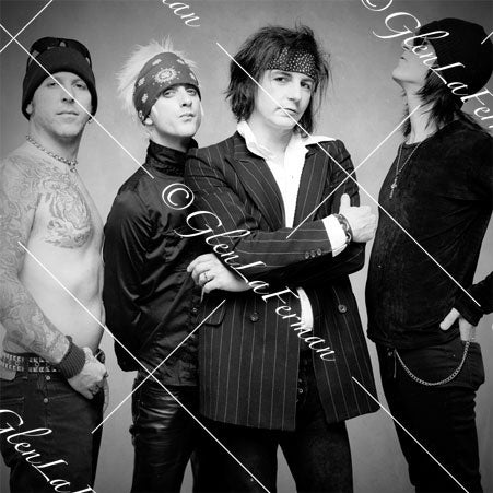 L.A. Guns close up, arms crossed, pinstriped suit