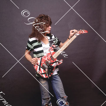 Eddie Van Halen in jeans looking at Kramer Frankenstrat