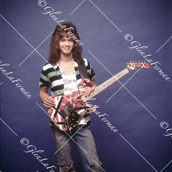 Eddie Van Halen in striped shirt looking at camera with Kramer Frankenstrat