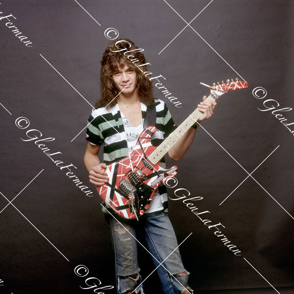 Eddie Van Halen in striped shirt and Kramer Frankenstrat with grey backdrop