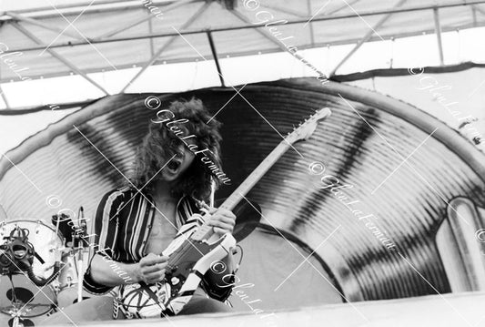 Eddie Van Halen in concert in striped shirt playing live