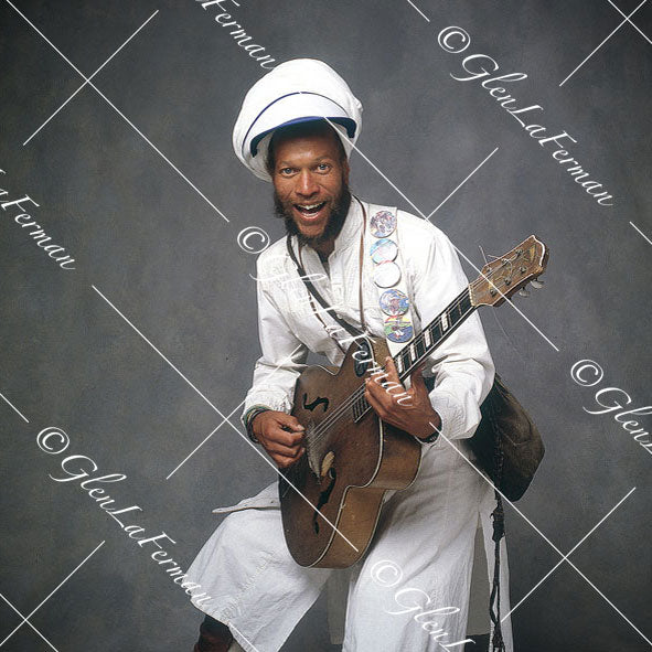 Harry Perry smiling, sitting with guitar