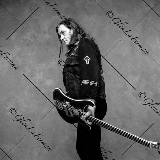 Lemmy Kilmister holding guitar, standing profile with signature look