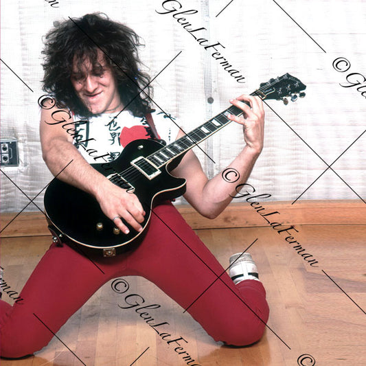 Vivian Campbell in red kneeling with Les Paul