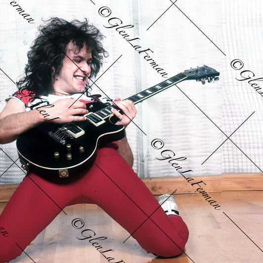 Vivian Campbell in red kneeling with Les Paul